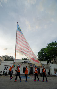 People by flags in city against sky