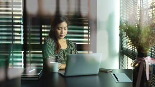 Woman using mobile phone while sitting on table