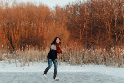 Smiling woman ice-skating on frozen lake