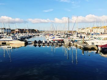 Boats moored at harbor against sky