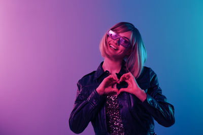 Portrait of young woman standing against blue background