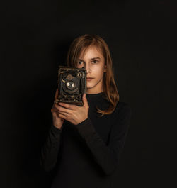 Portrait of a teenage boy photographing against black background