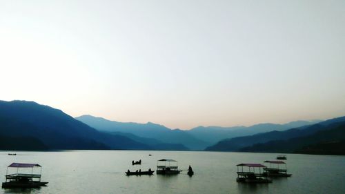 Boats sailing in lake against clear sky