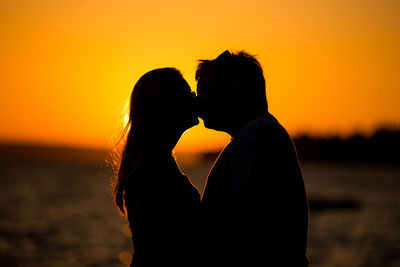 Side view of silhouette woman against sea during sunset