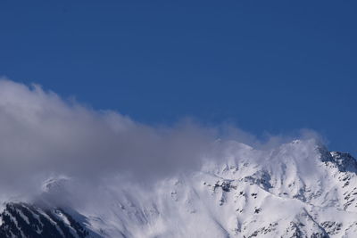 Scenic view of snowcapped mountains against blue sky