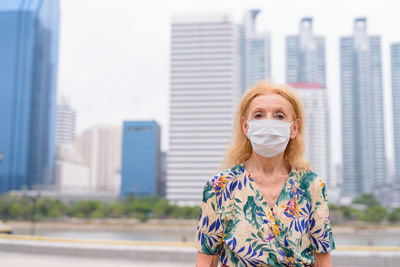 Portrait of woman against buildings in city