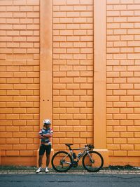 Man riding bicycle against brick wall