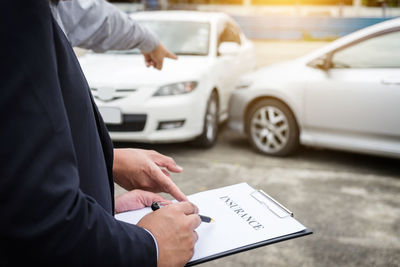 Midsection of businessman holding insurance paper with man