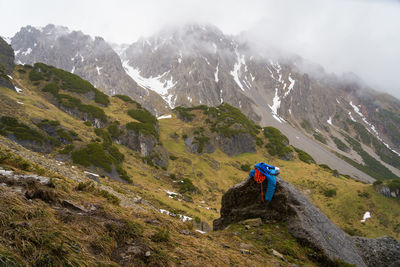 Rear view of man climbing on mountain against sky