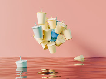 Many plastic cups levitating near planet earth on pink background. plastic pollution ecology 