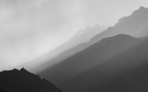 Scenic view of silhouette mountains during foggy weather