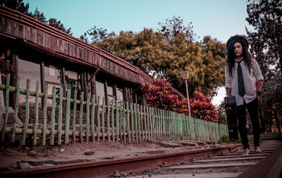 Full length of woman standing on railroad tracks against sky