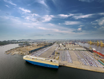 Aerial logistics commercial vehicles waiting to be load on to a car carrier ship at dockyard