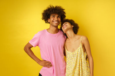 Portrait of young woman against yellow background