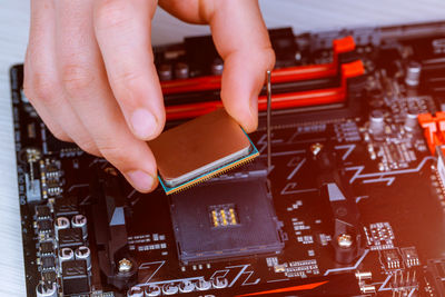 Cropped image of technician installing computer chip in circuit board