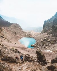 Men climbing on mountains against sky