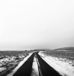 Empty road along landscape against clear sky