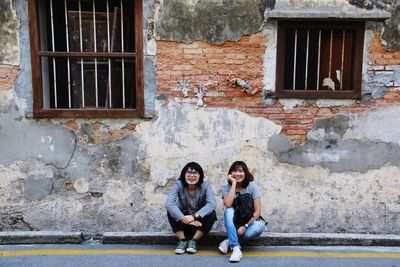 Portrait of smiling young woman sitting against building