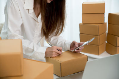 Midsection of woman holding paper while sitting in box