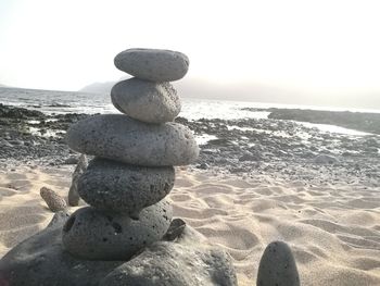 Stack of pebbles on beach against sky