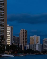 Modern buildings by sea against sky in city