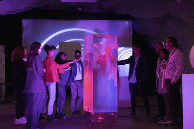 Multiracial business colleagues discussing over glass display during seminar in conference event