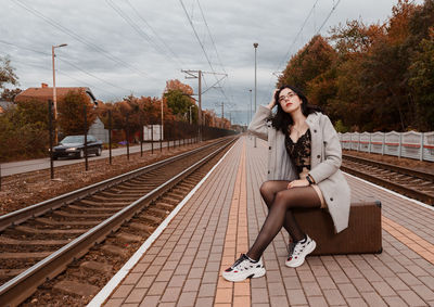 Full length of woman sitting on railroad tracks