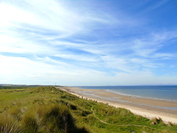 Scenic view of beach against cloudy sky