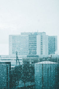 Modern cityscape against sky during winter