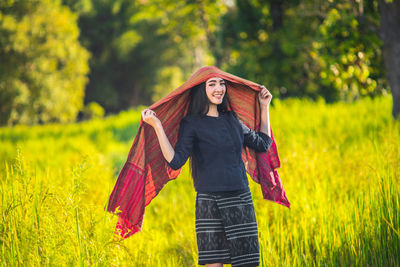 Portrait of happy young woman wearing shawl amidst grassy field