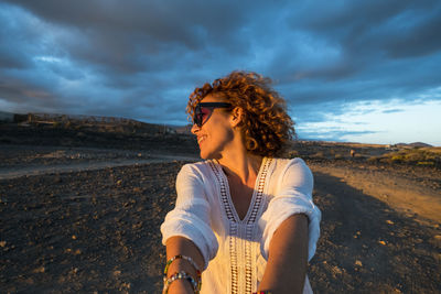 Young woman standing on sand at beach against sky
