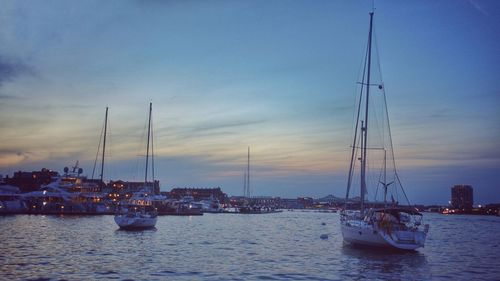 Sailboats sailing in sea against sky during sunset