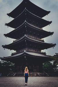 Low angle view of woman standing outside temple against sky