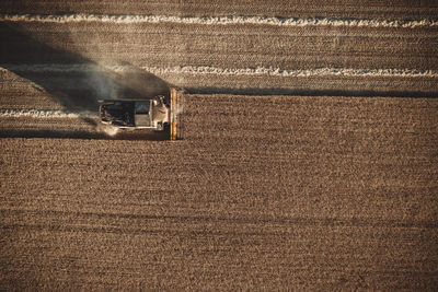 Combine harvester working at sunset from aerial view.