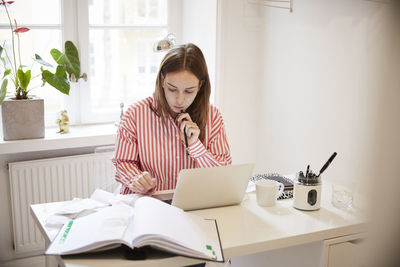 Young woman using phone while sitting on table