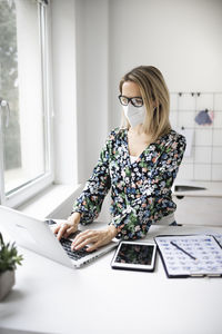 Woman using phone while sitting on table