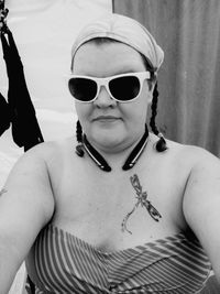 Portrait of overweight woman wearing sunglasses at beach