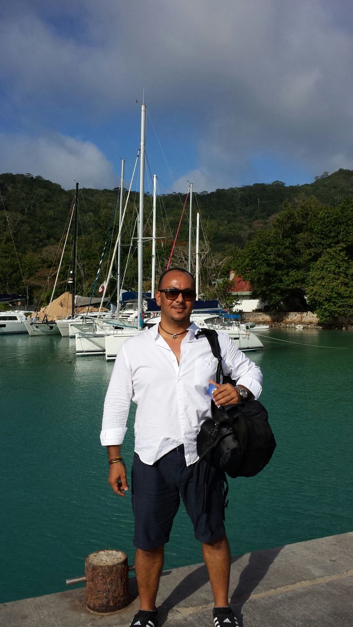 water, lifestyles, casual clothing, leisure activity, sky, person, standing, young adult, full length, looking at camera, nautical vessel, portrait, lake, young men, cloud - sky, front view, three quarter length