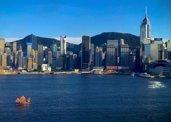 Modern buildings at victoria harbour against blue sky at dusk