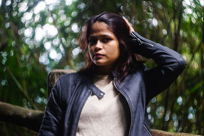 Portrait of young woman against trees in forest