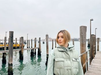 Portrait of young woman standing against clear sky