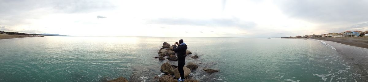 Rear view of people enjoying in sea against sky