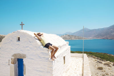 Greece, nikouria, tourist sunbathing on roof of small church