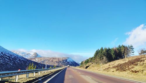 Road leading towards scotland mountains against blue sky