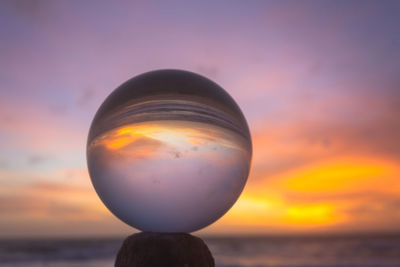 Close-up of crystal ball against sky during sunset