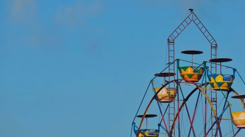 Low angle view of ferris wheel against blue sky