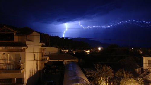 Lightning over illuminated city against sky at night