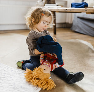 Full length of cute baby girl playing while sitting on floor at home