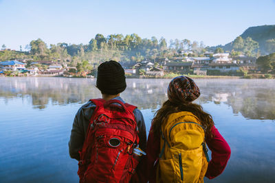 Rear view of people looking at river against sky