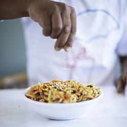 Close-up of person preparing food in bowl on table